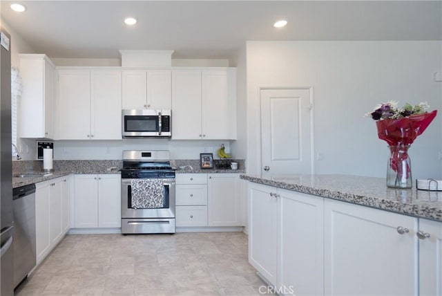 kitchen featuring recessed lighting, white cabinets, appliances with stainless steel finishes, and light stone countertops