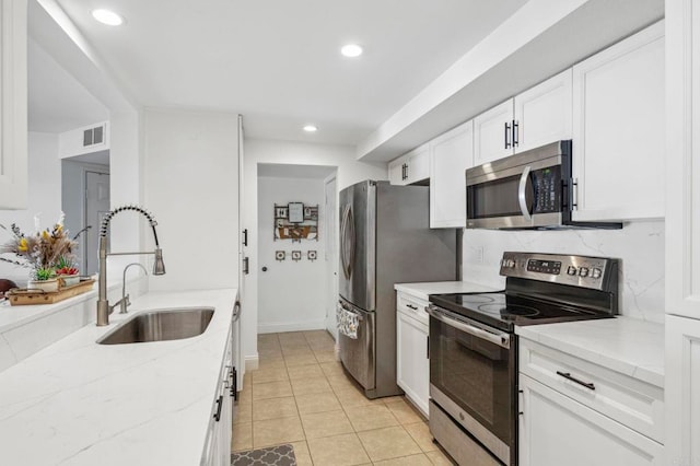 kitchen featuring a sink, stainless steel appliances, light stone counters, and white cabinetry