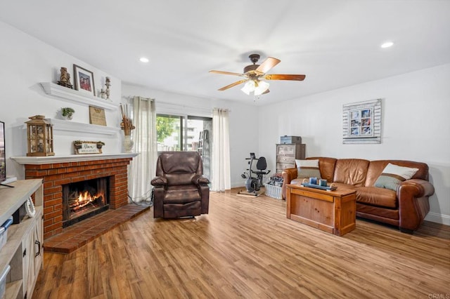 living room featuring wood finished floors, recessed lighting, a fireplace, baseboards, and ceiling fan