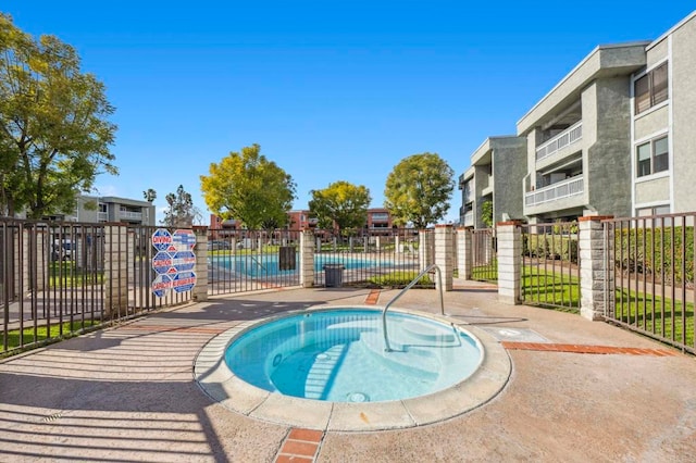 view of swimming pool featuring a hot tub and fence