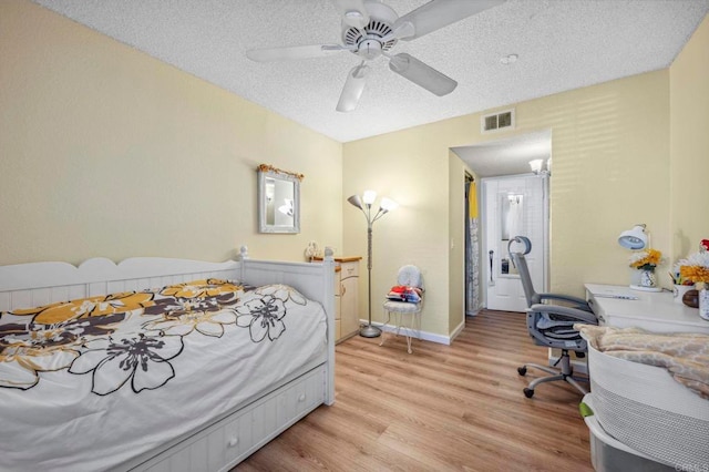 bedroom featuring a ceiling fan, baseboards, visible vents, a textured ceiling, and light wood-type flooring