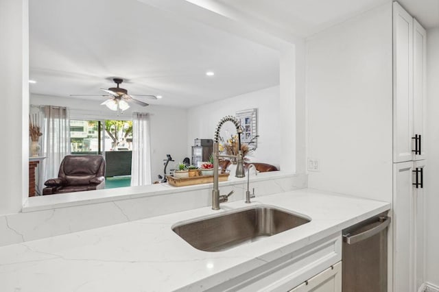 kitchen with dishwasher, light stone counters, white cabinetry, a ceiling fan, and a sink