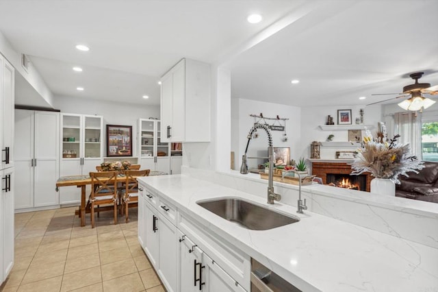 kitchen featuring white cabinets, light stone counters, light tile patterned floors, and a sink