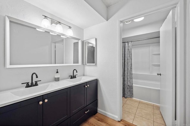 full bathroom with double vanity, tile patterned flooring, baseboards, and a sink