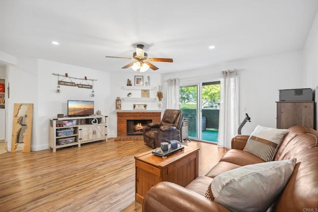 living room with recessed lighting, light wood-style flooring, a brick fireplace, and ceiling fan