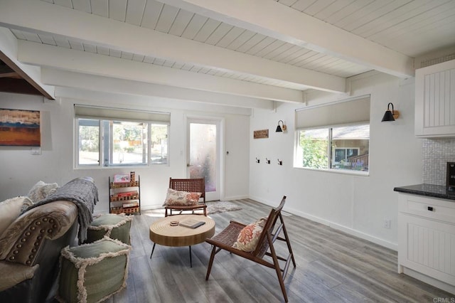 living area with beamed ceiling, wood finished floors, and baseboards