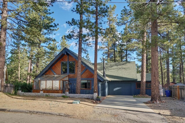 view of front facade with an attached garage, concrete driveway, board and batten siding, and fence