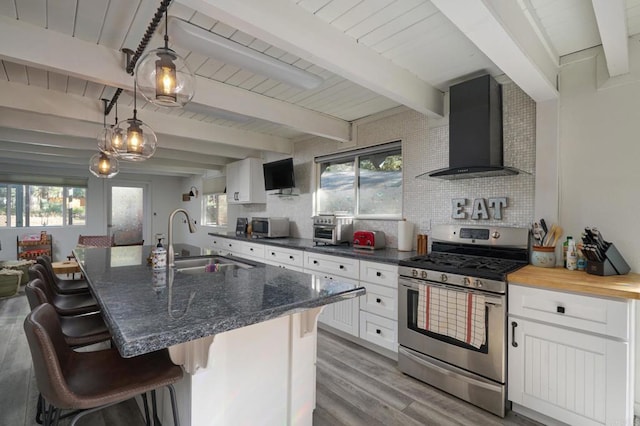 kitchen featuring tasteful backsplash, stainless steel appliances, wall chimney range hood, and a sink