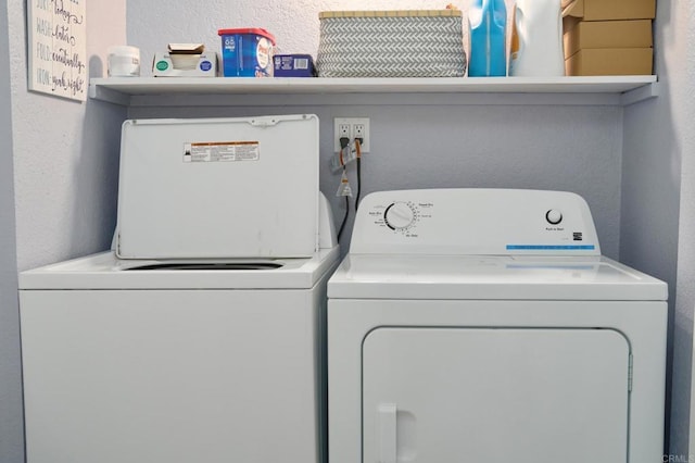 clothes washing area featuring independent washer and dryer and a textured wall