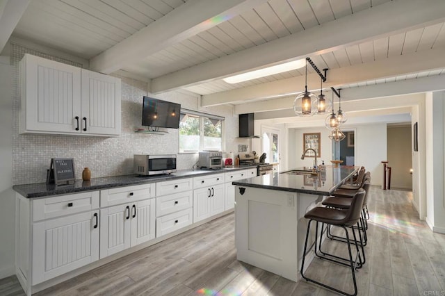 kitchen with stainless steel microwave, light wood-style flooring, tasteful backsplash, and a sink