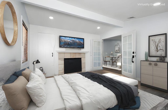 bedroom with visible vents, lofted ceiling with beams, recessed lighting, a fireplace, and wood finished floors