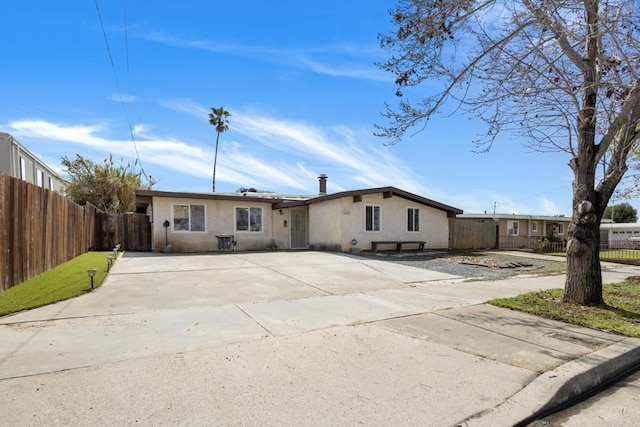 view of front of home with stucco siding, driveway, and fence