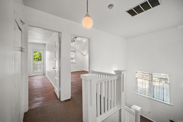 hallway featuring visible vents, an upstairs landing, and dark wood-type flooring