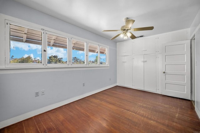 unfurnished bedroom featuring a closet, a ceiling fan, baseboards, visible vents, and dark wood-style flooring