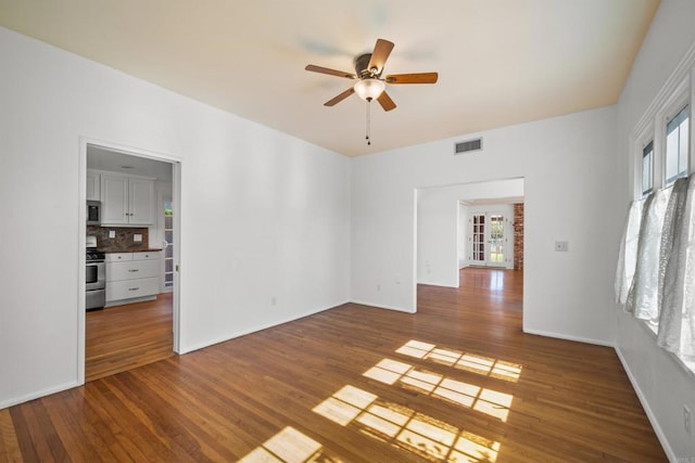 unfurnished room with hardwood / wood-style floors, baseboards, visible vents, and a ceiling fan