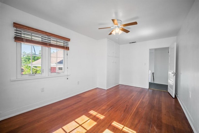 spare room with baseboards, visible vents, ceiling fan, and wood-type flooring