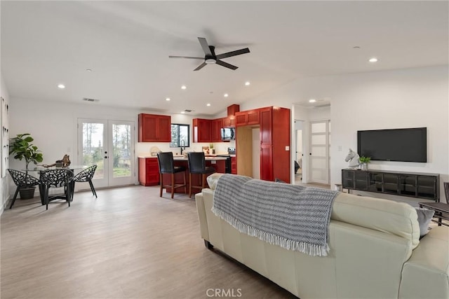 living area featuring visible vents, light wood-style flooring, recessed lighting, ceiling fan, and vaulted ceiling