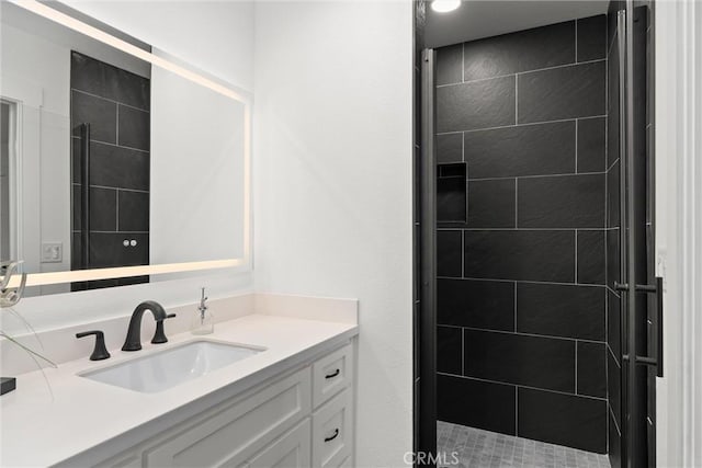 bathroom featuring tiled shower and vanity