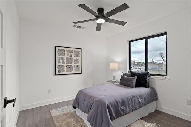 bedroom featuring ceiling fan, wood finished floors, visible vents, and baseboards