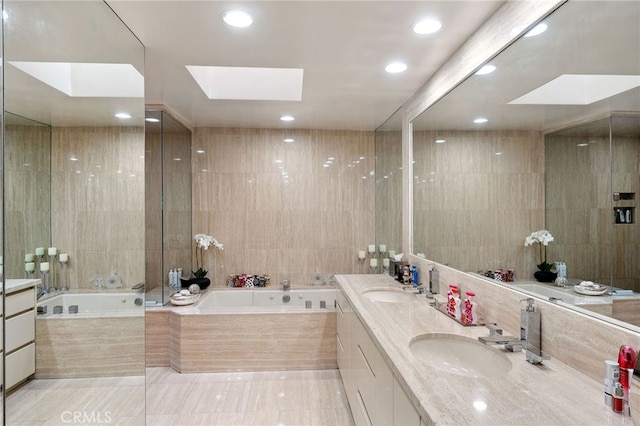 full bathroom with a skylight, tile walls, a garden tub, and a sink