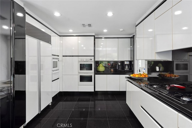 kitchen with dark countertops, white cabinetry, and modern cabinets