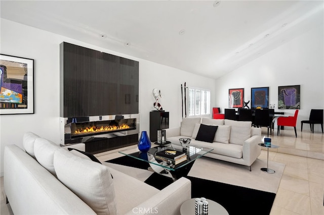 living area featuring light tile patterned floors, a glass covered fireplace, and vaulted ceiling