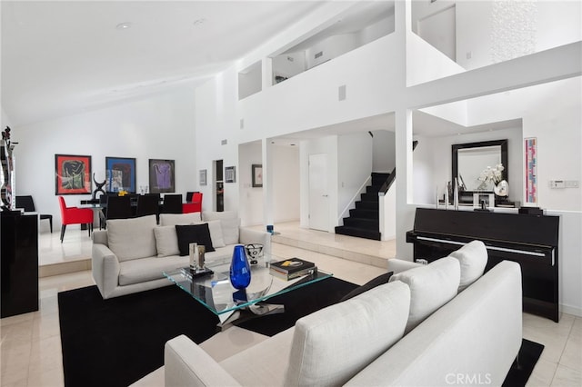 living room featuring high vaulted ceiling, light tile patterned flooring, and stairs