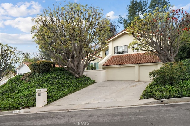 view of front facade featuring stucco siding, concrete driveway, an attached garage, and a tile roof