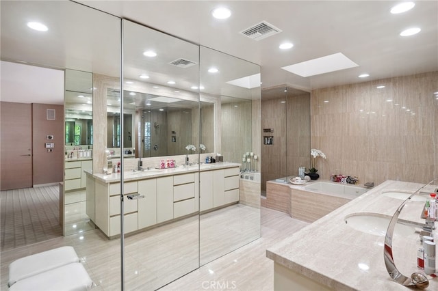 bathroom featuring a sink, visible vents, a garden tub, and two vanities