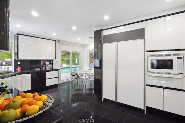 kitchen with built in appliances, dark countertops, modern cabinets, and white cabinetry