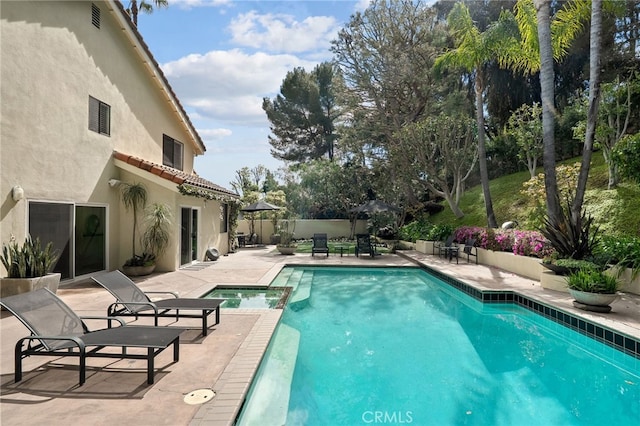 view of swimming pool featuring a patio area, fence, and a pool with connected hot tub