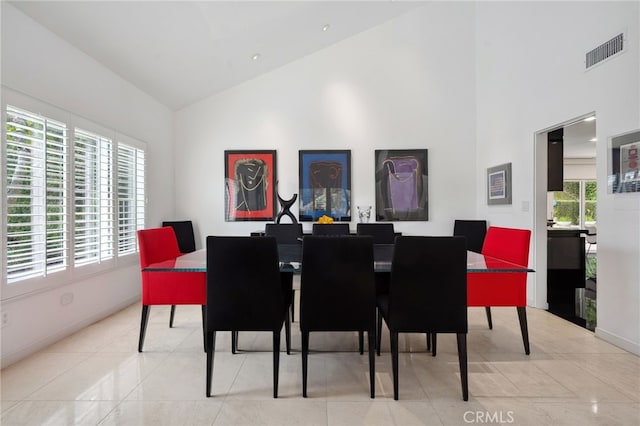 tiled dining room with visible vents, plenty of natural light, high vaulted ceiling, and baseboards