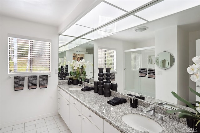 bathroom featuring a sink, double vanity, a stall shower, and tile patterned floors