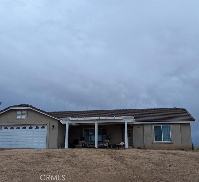 ranch-style home with stucco siding, a patio, an attached garage, and a tiled roof