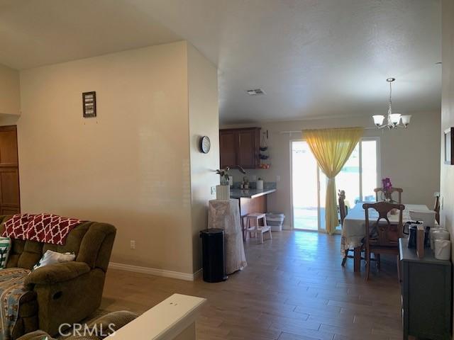 living area with a notable chandelier, light wood-style floors, visible vents, and baseboards