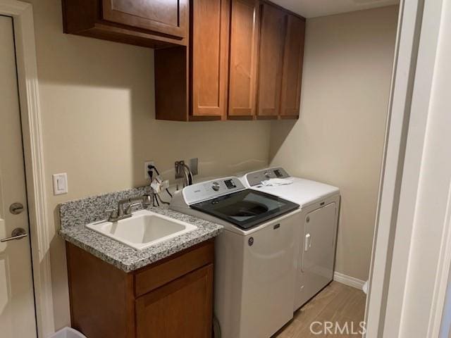 washroom with a sink, cabinet space, light wood finished floors, and washer and clothes dryer