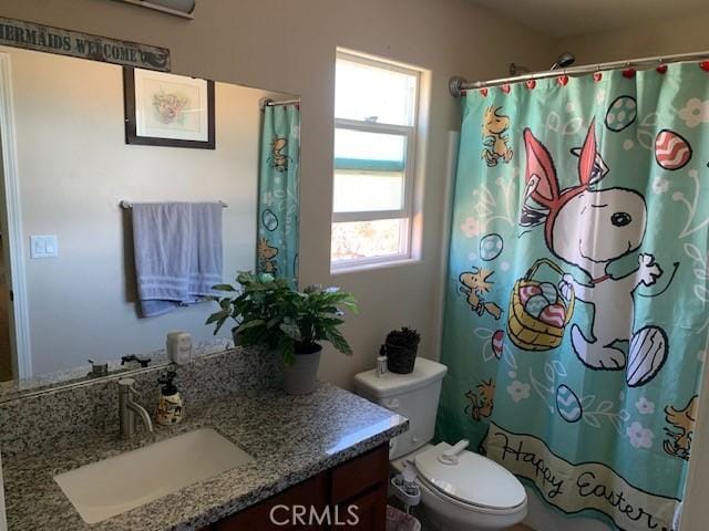 bathroom featuring toilet, vanity, and a shower with curtain