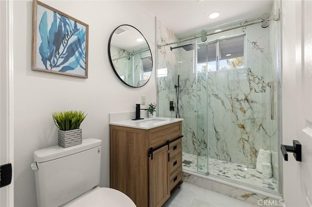 bathroom with vanity, toilet, marble finish floor, and a marble finish shower