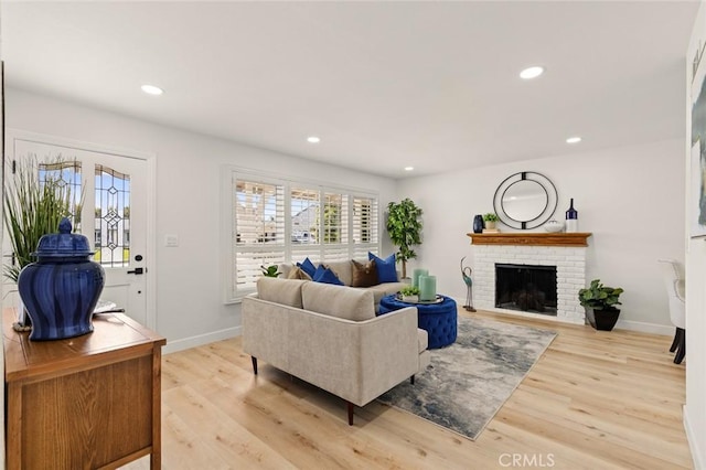 living area with recessed lighting, baseboards, a brick fireplace, and light wood finished floors