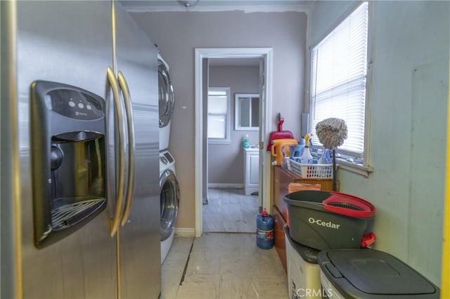 laundry area with laundry area, stacked washer / dryer, and baseboards