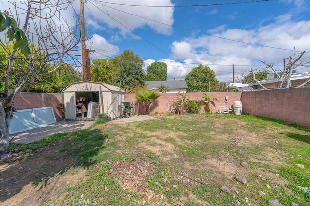 view of yard with a storage shed, a fenced backyard, and an outbuilding