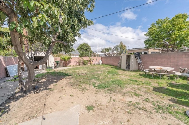 view of yard featuring a shed, an outdoor structure, and a fenced backyard