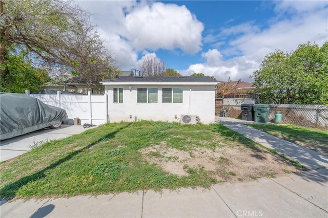 view of front of home featuring ac unit, stucco siding, a front yard, and fence