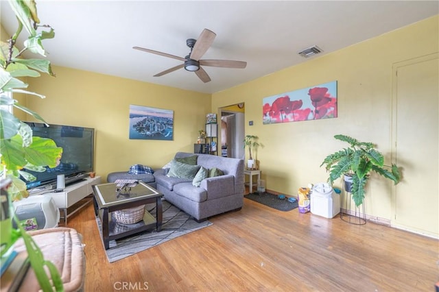 living area featuring baseboards, wood finished floors, visible vents, and ceiling fan