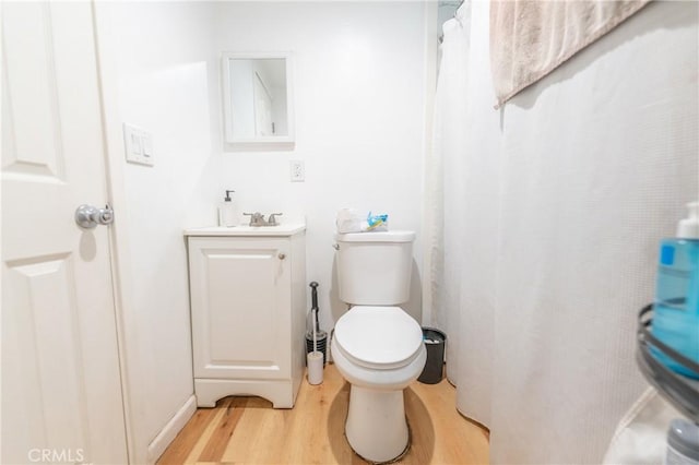 bathroom with toilet, vanity, and wood finished floors