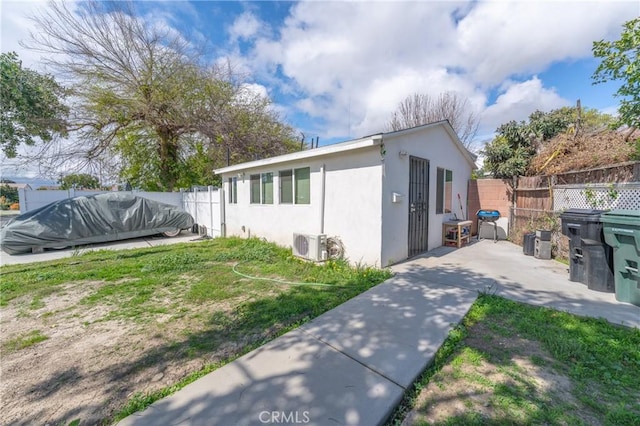 view of side of property with ac unit, stucco siding, a fenced in pool, and fence