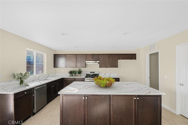 kitchen with visible vents, a kitchen island, a sink, stainless steel appliances, and under cabinet range hood