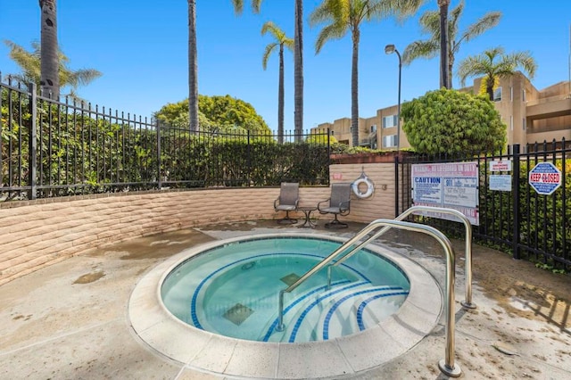 view of pool with a community hot tub and fence