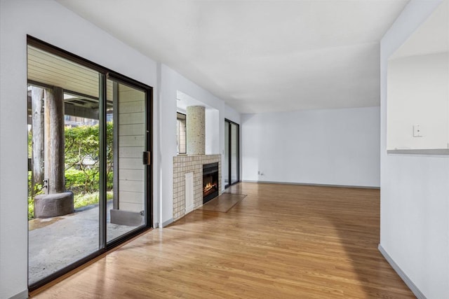 unfurnished living room featuring a fireplace, baseboards, and wood finished floors