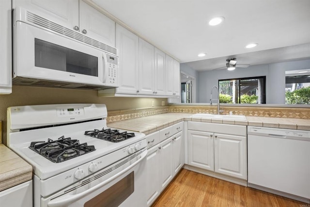 kitchen featuring white appliances, white cabinetry, light wood-type flooring, and a sink